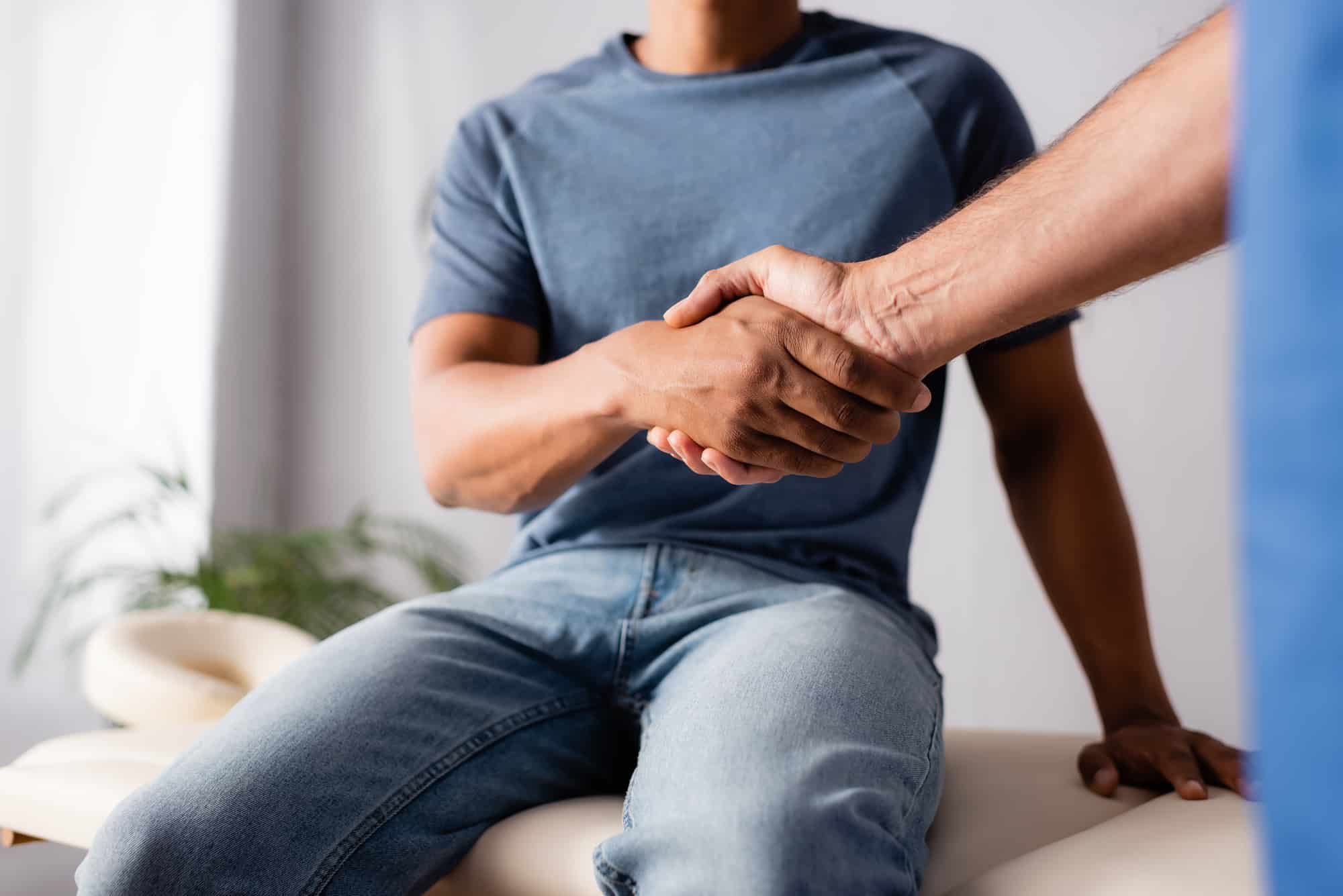 chiropractor shaking hands with male patient