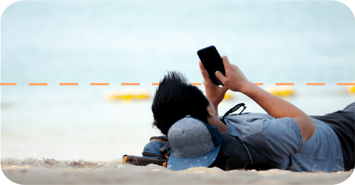 man relaxing on beach while looking at phone