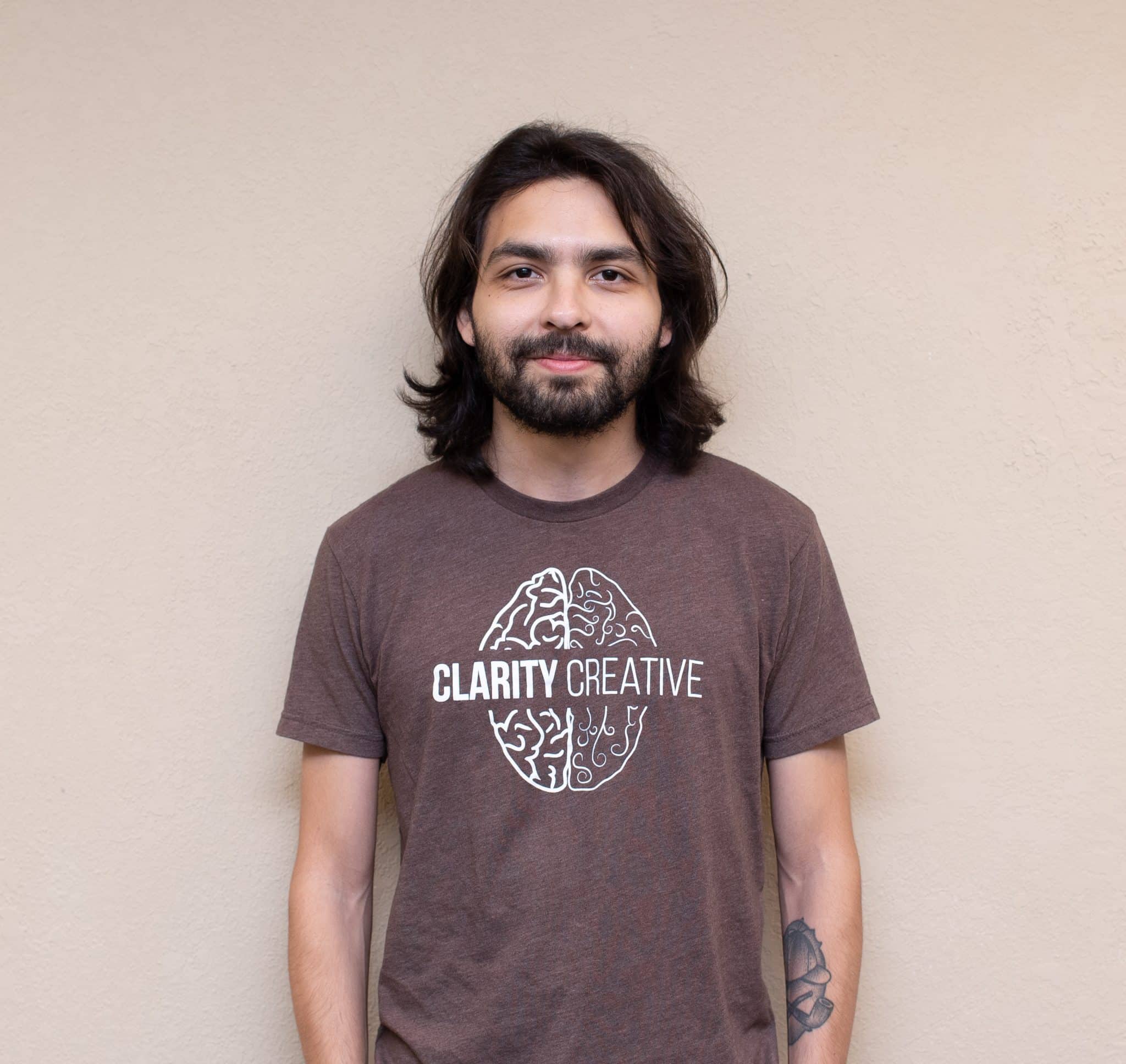 Matt from Clarity Creative. He is wearing a brown Clarity shirt and has shoulder length brown hair with a beard and mustache.